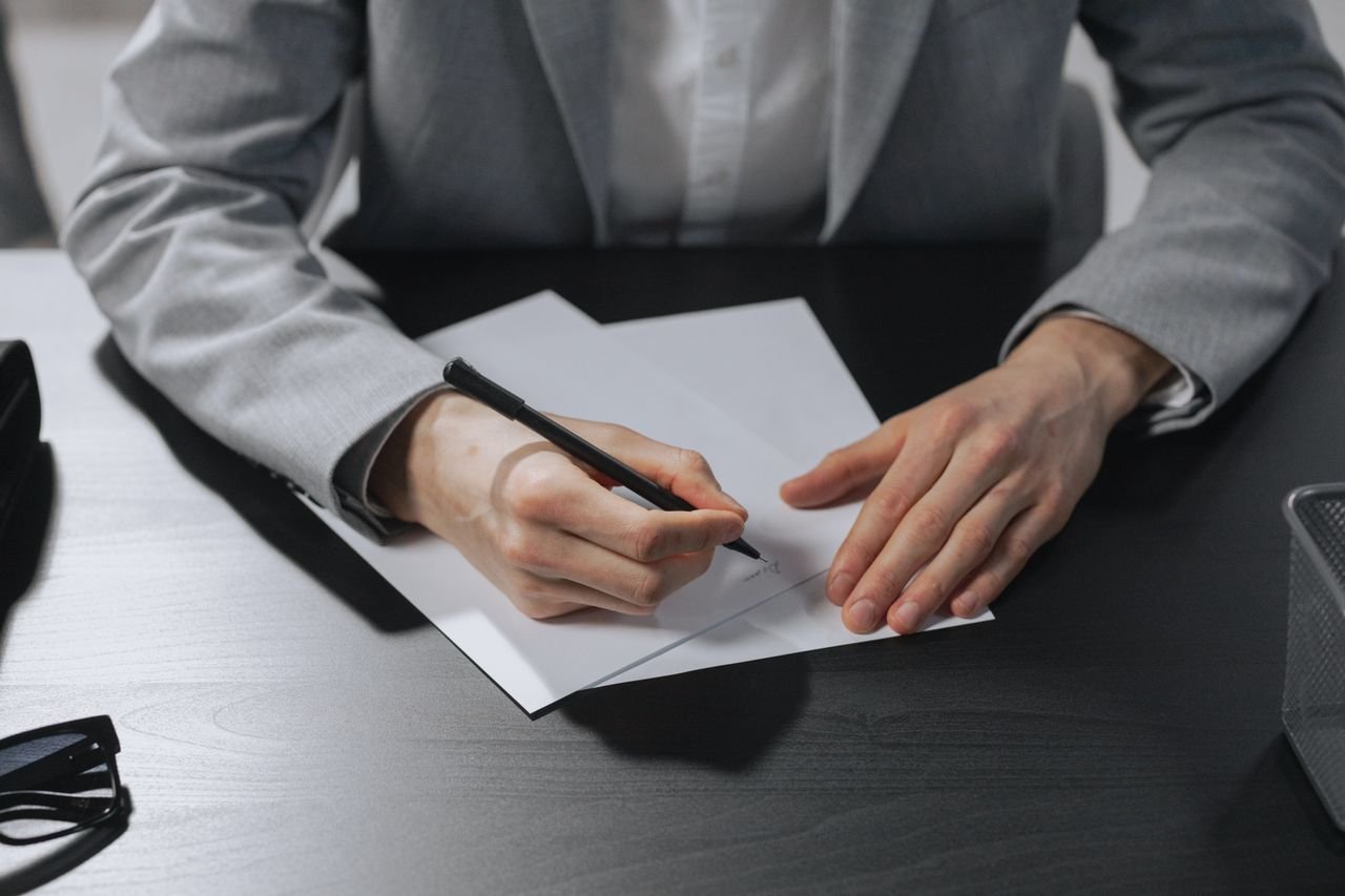 Writing on paper at desk in business suit